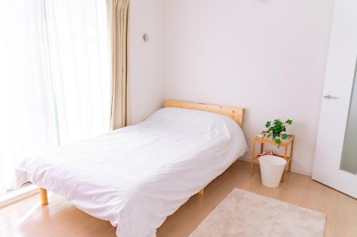 uma cama branca num quarto com uma janela em One Point Five em Tóquio
