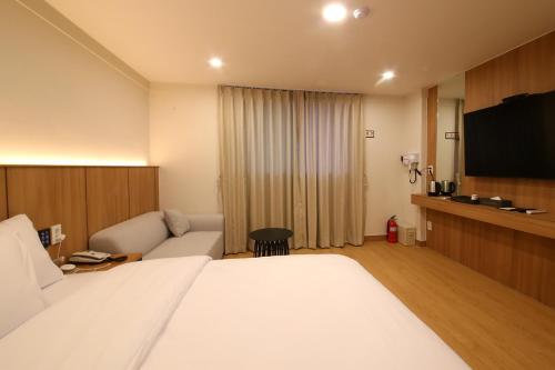 a hotel room with a bed and a flat screen tv at MGM Hotel in Gangneung