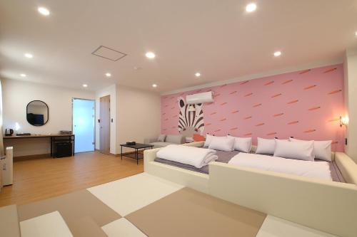 a bedroom with a large bed and a pink wall at MGM Hotel in Gangneung