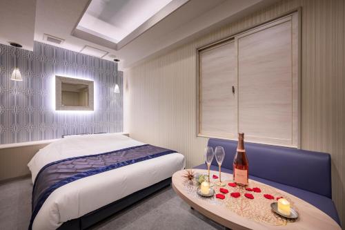 東京的住宿－Hotel Plantan - Adult Only，一间卧室配有一张床和一张桌子及一瓶葡萄酒