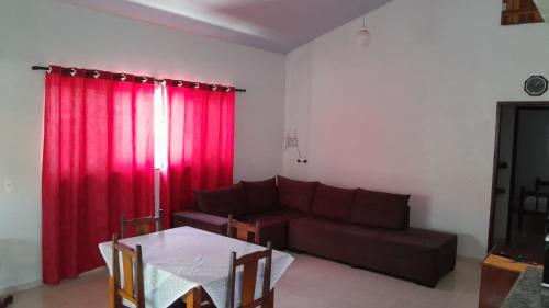uma sala de estar com um sofá e cortinas vermelhas em Casa Maria em Pirenópolis