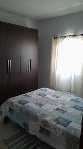 um quarto com uma colcha numa cama e uma janela em Casa Maria em Pirenópolis