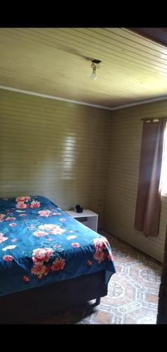 um quarto com uma cama com um cobertor azul com flores em Cabañas Guaimbe em Eldorado