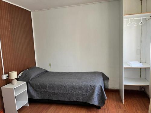 um quarto com uma cama e uma prateleira branca em Departamentos Arrayán em Chillán