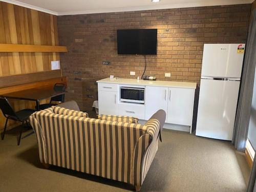 a kitchen with two couches and a white refrigerator at Allara Motor Lodge in Bendigo