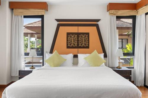 1 dormitorio con 1 cama blanca grande y ventanas en Laguna Village 3 Bedroom Villla, en Layan Beach