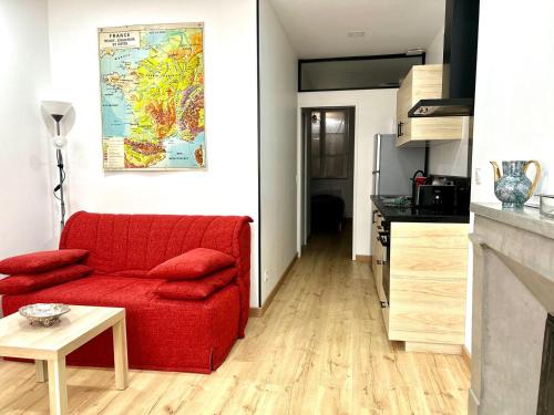 a living room with a red couch and a kitchen at Cathedral: Cosy in the heart of the city center in Poitiers