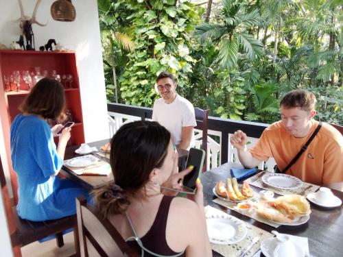 Eine Gruppe von Menschen, die an einem Tisch sitzen und Essen essen. in der Unterkunft Green turf in Galle