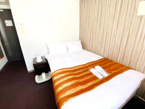 WEB Hotel Tokyo Asakusabashi / Vacation STAY 8771 في طوكيو: غرفة فندقية عليها سرير وعليها نعال اثنين