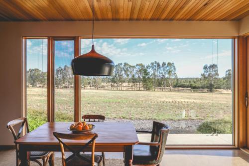 a dining room with a table and chairs and a large window at Luxury Retreat at Barham Avocados in Barham