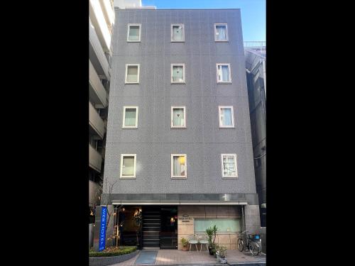 a tall gray building with windows on a street at Web Hotel Tokyo Asakusabashi in Tokyo