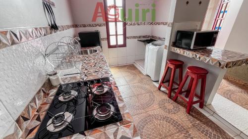 a kitchen with a stove and two red stools at Departamento cómodo y céntrico in Cobija