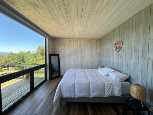 a bedroom with a large bed and a balcony at Casa Flor del Lago in Villarrica