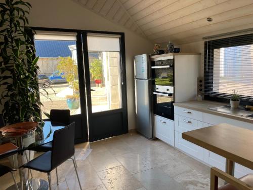 une cuisine avec un réfrigérateur et une table et un tableablish dans l'établissement Ancien Fournil Cosy avec Piscine Couverte, Parc Verdoyant et Sauna, à 30 mn du Mans - FR-1-410-432, à Vivoin