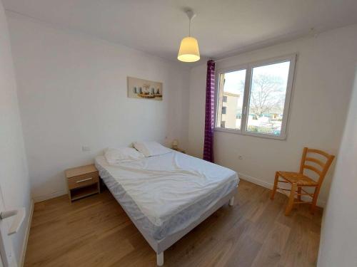 une chambre avec un lit, une fenêtre et une chaise dans l'établissement Appartement 4 pièces à Marseillan Plage, proche de la mer, avec parking et équipements complets - FR-1-326-799, à Marseillan
