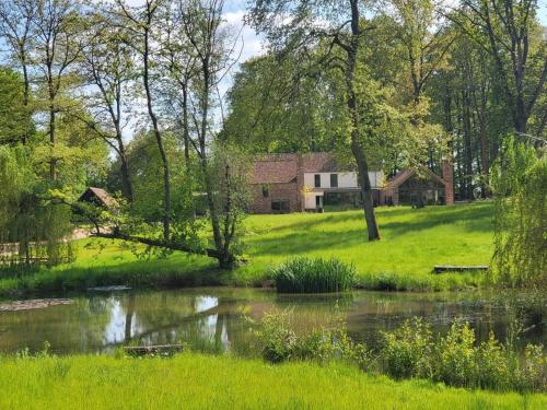 a house in the middle of a field with a pond at Private 2 Bedroom Apartment at Woodland Retreat in Gamlingay
