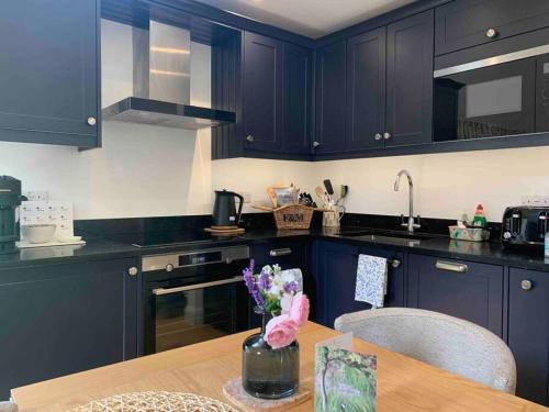 a kitchen with dark blue cabinets and a wooden table at Private 2 Bedroom Apartment at Woodland Retreat in Gamlingay