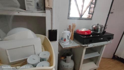a kitchen with a shelf with dishes and a stove at Kochimoto Bed & Bath in Baguio