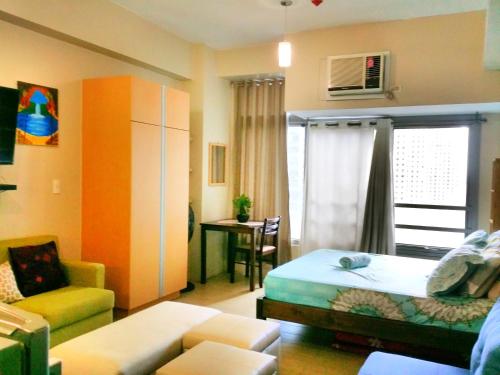 ein Schlafzimmer mit einem Bett, einer Couch und einem Sessel in der Unterkunft Studio-Type Condo at Eastwood Legrand 3 in Manila
