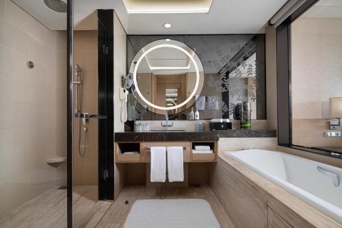 a bathroom with a tub and a sink and a mirror at Crowne Plaza Guangzhou Huadu by IHG - Free Shuttle bus between hotel to Exhibition Center During Canton Fair in Guangzhou