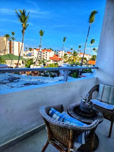 a balcony with a table and chairs and palm trees at Beach Sun Caribbean and Ducassi in Punta Cana