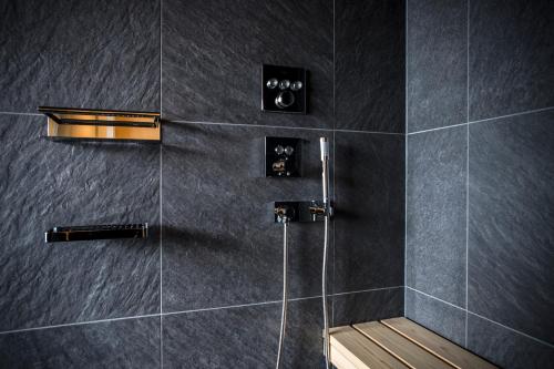 a bathroom with a shower with black tiles at Hotel Kitanoya in Miyazu