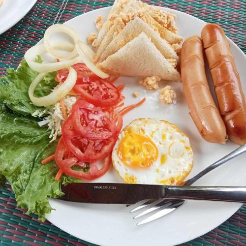 a plate of food with an egg and tomatoes and bread at Malee homestay in Ko Por