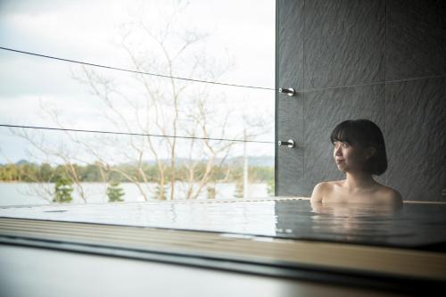 a woman sitting in a bath tub with a window at Hotel Kitanoya in Miyazu