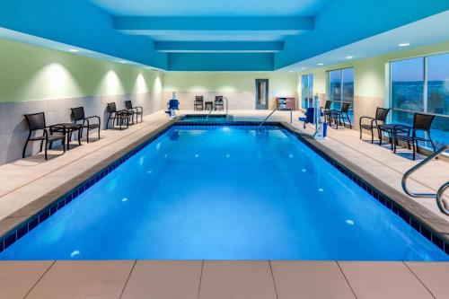 - une piscine dans une chambre d'hôtel dotée de tables et de chaises dans l'établissement Holiday Inn Express & Suites - Colorado Springs South I-25, an IHG Hotel, à Colorado Springs