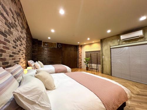 a bedroom with two beds and a brick wall at S-asakusa in Tokyo