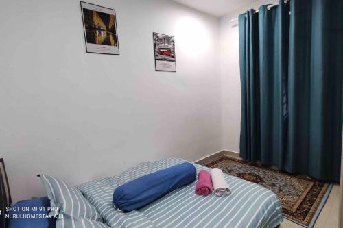 a bed in a room with a blue curtain at Nurul Homestay Ajil in Bukit Payong