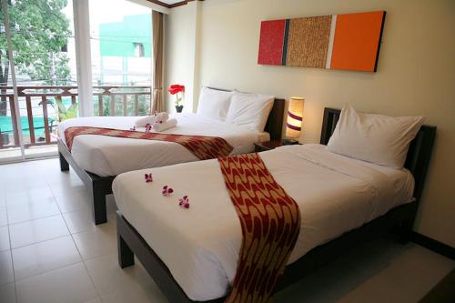 una habitación de hotel con 2 camas con flores. en Khon Kaen Orchid Hotel, en Khon Kaen