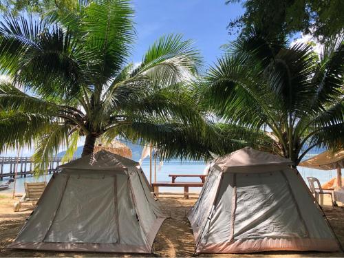 two tents sitting next to palm trees on the beach at Malee homestay in Ko Por