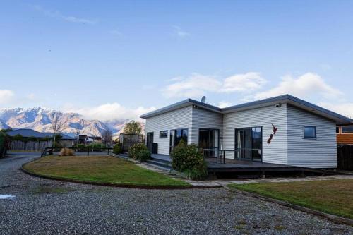 レイク・ハウェアにあるPeaceful Hawea Escapeの山を背景にした小さな白い家