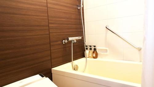 a bathroom with a tub and a toilet and a shower at Chateraise Hotel Nagano in Nagano