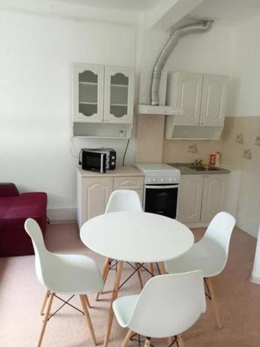 eine Küche mit einem Tisch und weißen Stühlen im Zimmer in der Unterkunft Гостиница АО Аксайавтотранс in Aksay