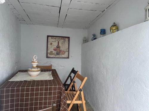einen Tisch und einen Stuhl in einem Zimmer mit einem Tisch und einem Bild in der Unterkunft Casa Miguelito in Comares