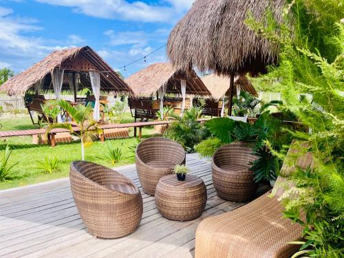 a deck with rattan wicker chairs and huts at La Palapa Inn Port Barton in San Vicente
