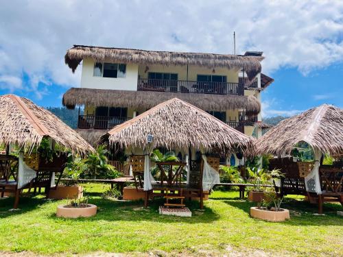 a building with thatched umbrellas and tables in front of it at La Palapa Inn Port Barton in San Vicente