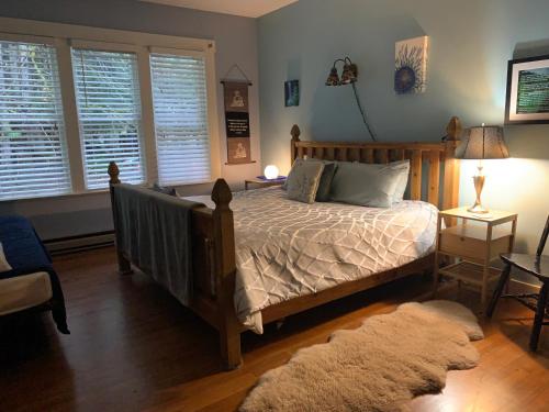 a bedroom with a bed and two windows and a rug at Mountain Meadows Inn & Chalet Suites in Ashford