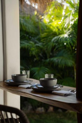 a wooden table with two cups and plates on it at Casa MexiBali, Palapita in Troncones
