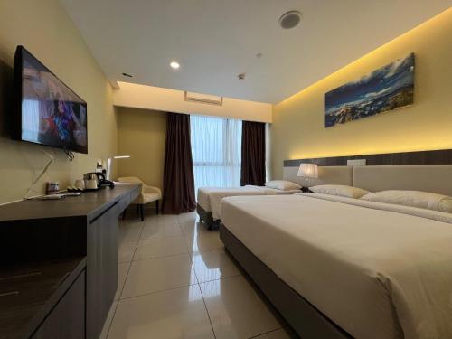 a hotel room with two beds and a flat screen tv at QUINCE HOME GRAND ION DELEMEN GENTING HIGHLANDs in Genting Highlands