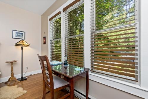 a table and a chair in a room with windows at Mountain Meadows Inn & Chalet Suites in Ashford