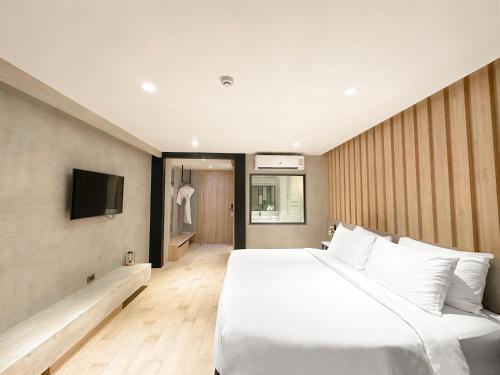 a bedroom with a large white bed and a tv at Loft Bangkok Hotel in Bangkok