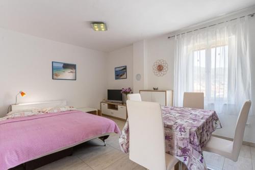 a white bedroom with a pink bed and a table at Apartment Mici 2 - great loaction and relaxing in Cres