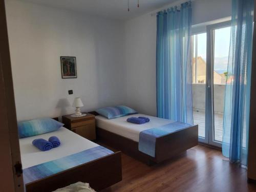 - une chambre avec 2 lits dotés d'oreillers bleus et d'une fenêtre dans l'établissement Apartment Anec - 150m from the sea, à Supetar