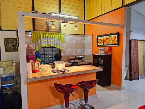 una cucina con pareti arancioni e sgabelli rossi di Homestay D'Lempor 