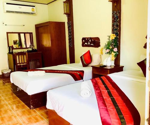 a hotel room with three beds in a room at Mitkhoonyoum Hotel in Ban Khun Yuam