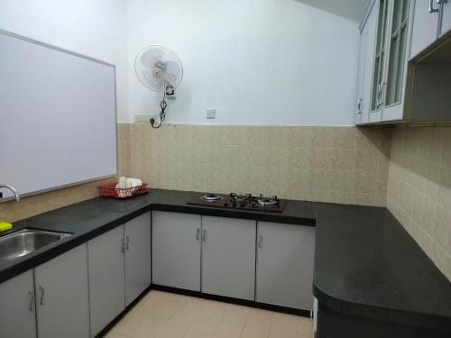 a kitchen with white cabinets and a sink and a fan at CMN Hotel & Homestay in Sungai Petani