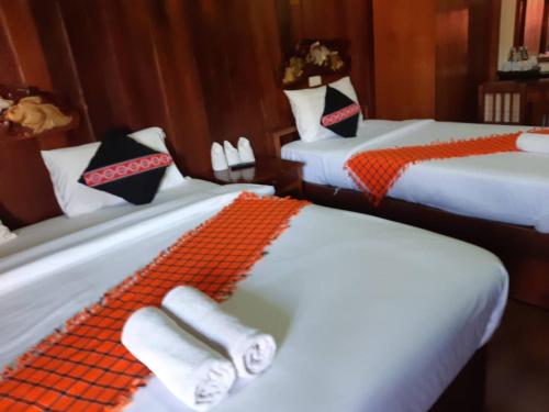 Mitkhoonyoum Hotel في Ban Khun Yuam: غرفة بسريرين مع وسائد برتقالية وسوداء